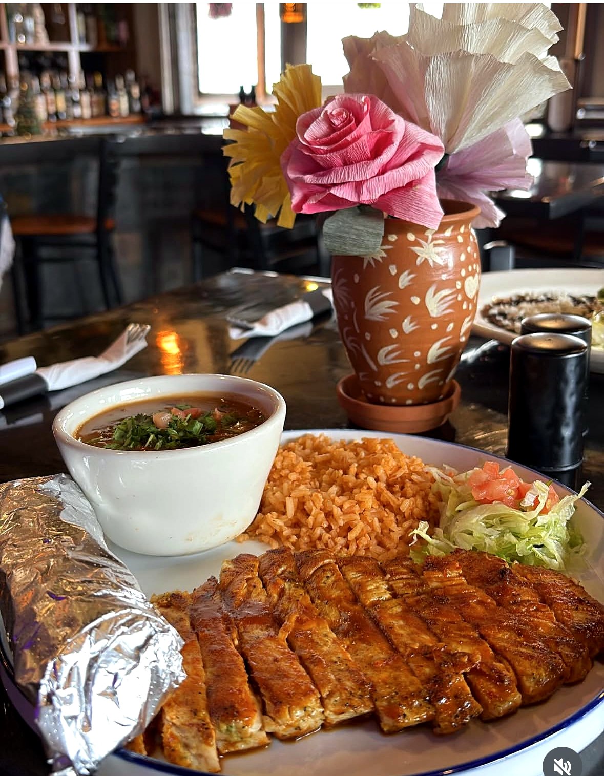 Grilled chicken plate with rice, beans, and birria consomé at Mila's Cantina