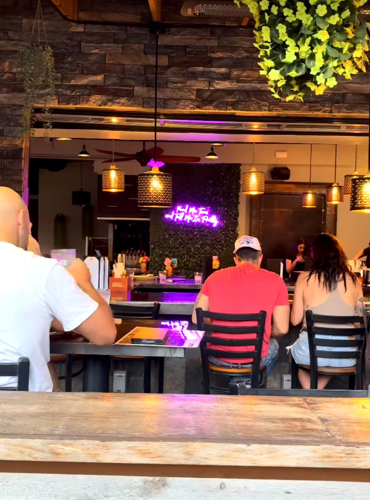Mila's Cantina dining room with string lights, neon sign, and communal tables
